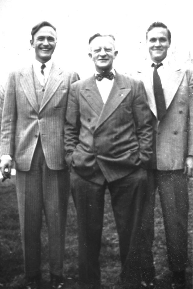 Three Paulson men in suits, photographed outdoors